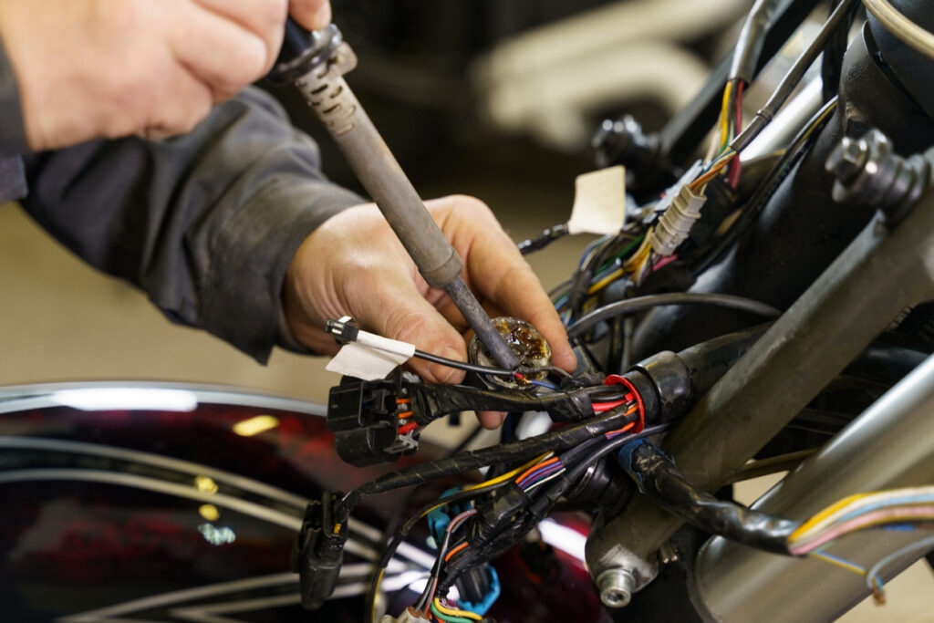 Un electricista está soldando cables eléctricos a equipos eléctricos en una motocicleta. De cerca. Concepto de transporte